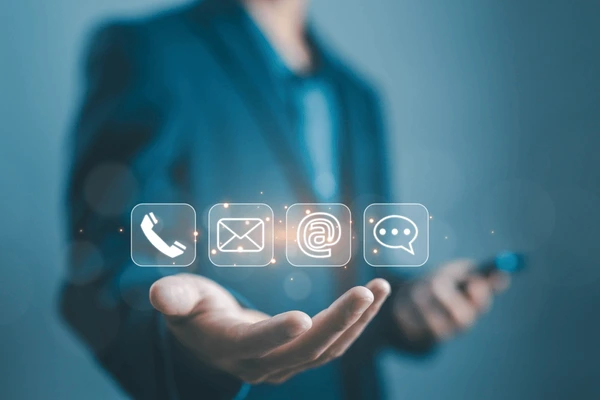 Business professional holding digital contact icons representing phone, email and chat support
